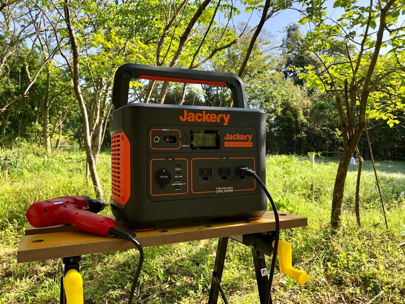Jackeryポータブル電源1000を実際にキャンプ場で使う、電動ドライバーを接続し、背景には森が写っている