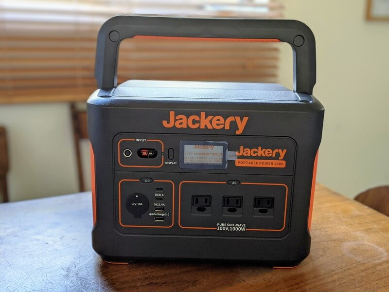 Jackeryポータブル電源1000を家庭のテーブルの上に置いている様子。ハンドルを上げた状態、正面からの写真