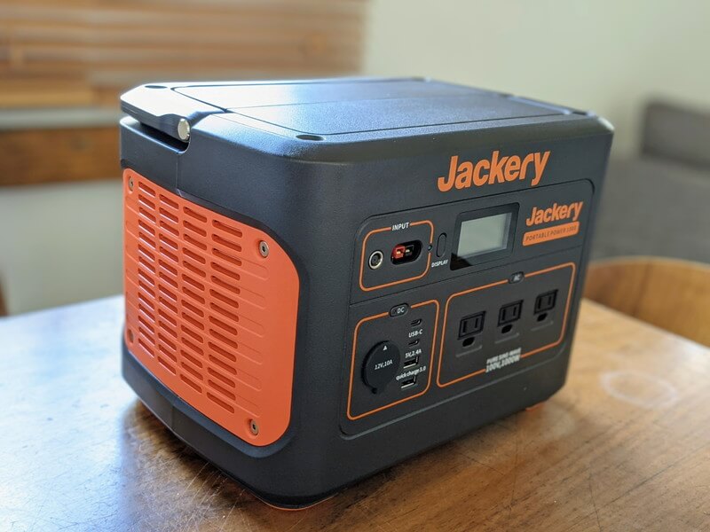 Jackeryポータブル電源1000を家庭のテーブルの上に置いている様子。ハンドルを下げ、左側面の写真